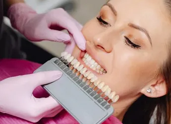 Dentist holding up shade guide to a patient's teeth