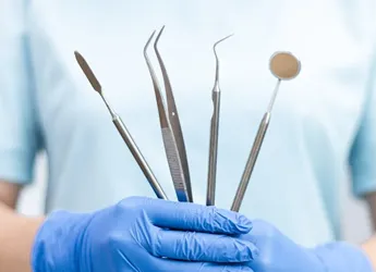 Dentist holding dental tools with blue gloves